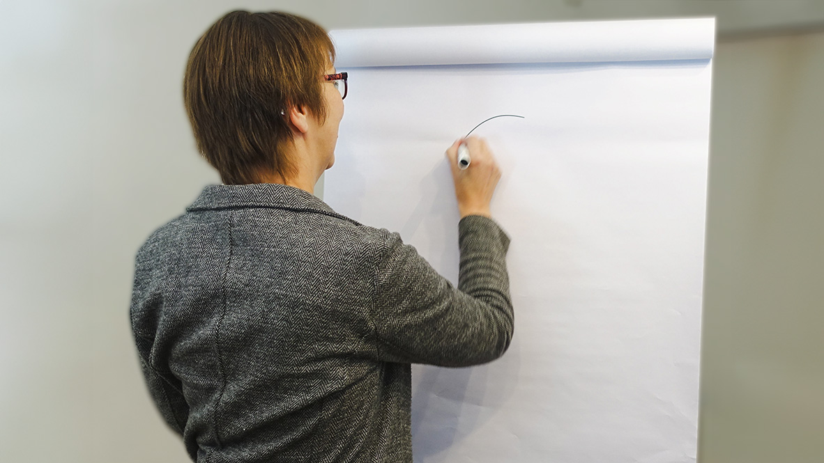 Christa Hübner vor einer Flipchart malt einen Kreis auf das Papier.